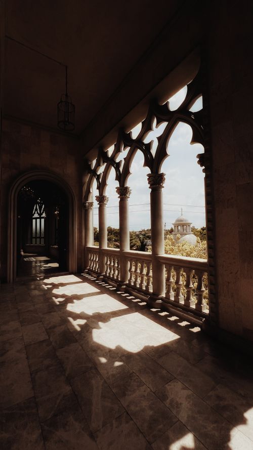 Free A Gothic corridor with ornate arches and a scenic view beyond. Stock Photo