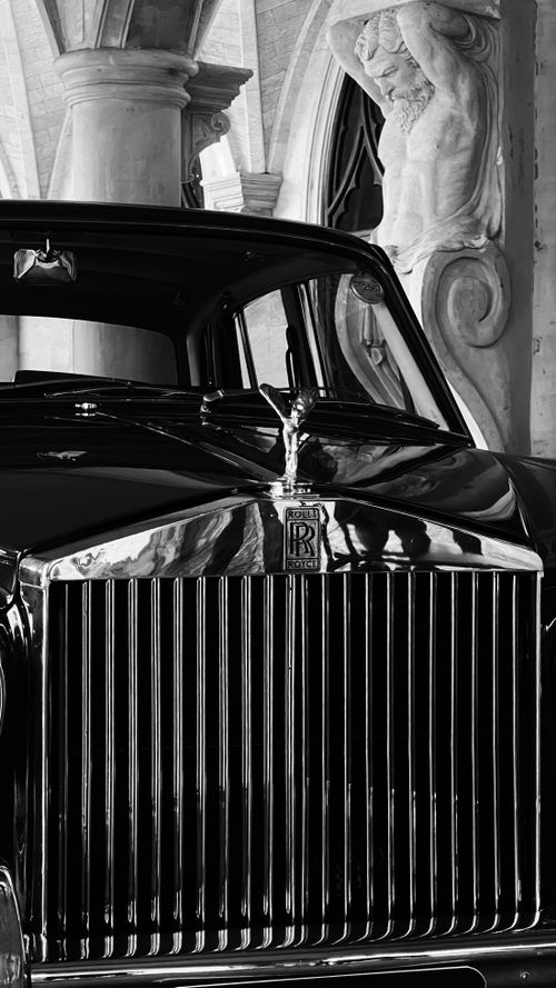 Free Close-up of a vintage luxury car in black and white with architectural backdrop. Stock Photo