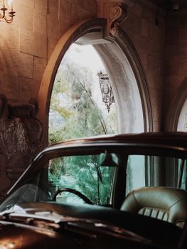 Vintage car interior with elegant window view in classic mansion setting, exuding luxury and nostalgia.