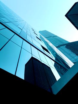 Low angle shot of modern skyscrapers with glass facades reflecting the sky.