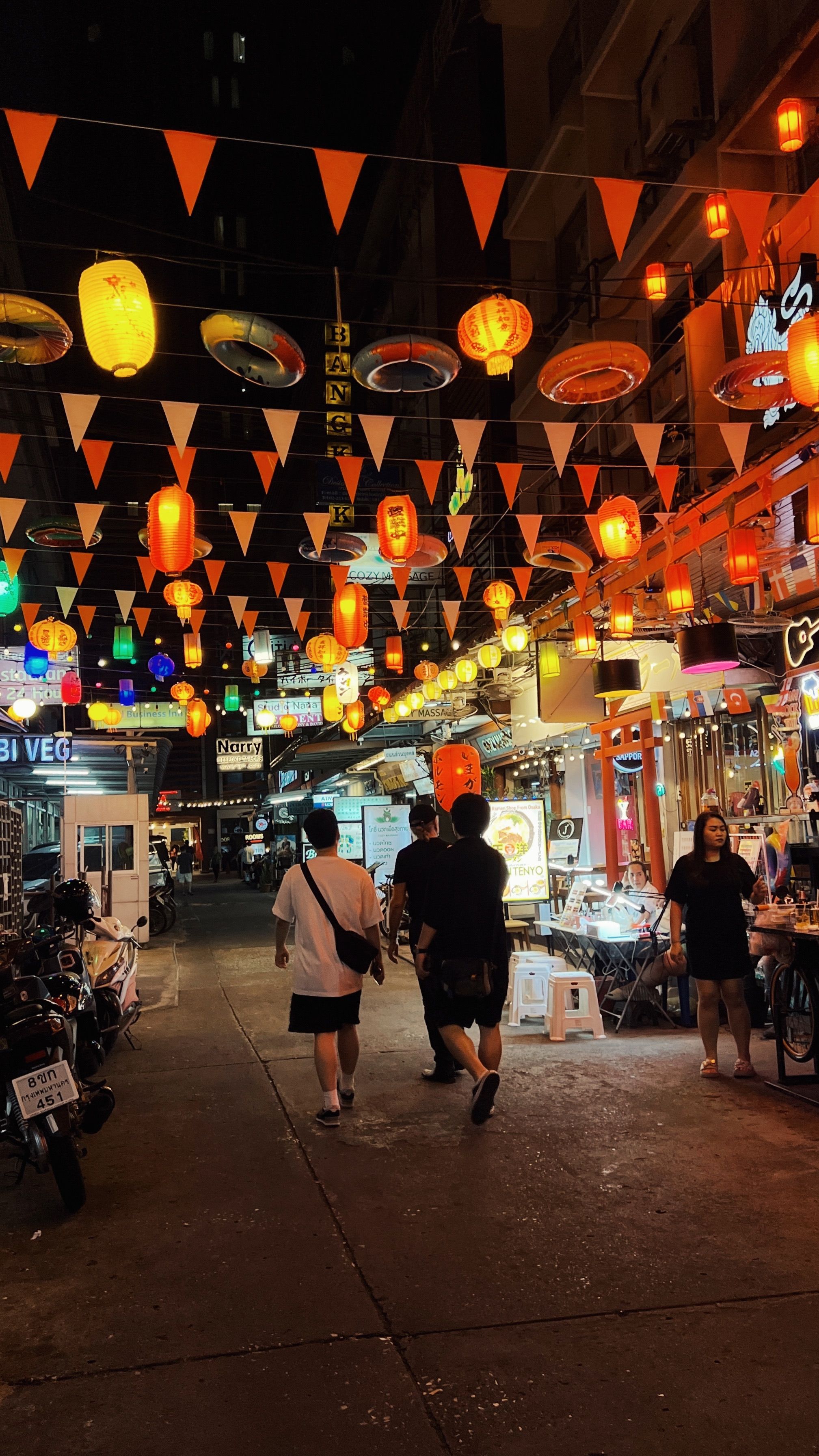 A bustling city night market adorned with colorful lanterns and vibrant lights.