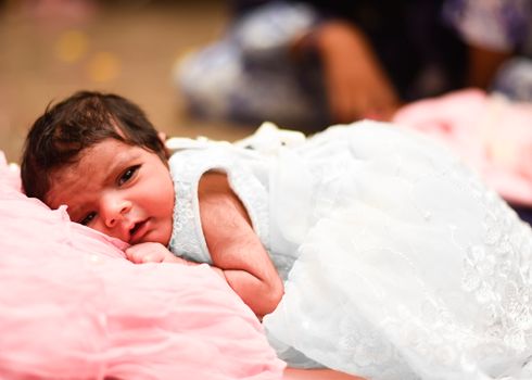 Adorable baby lying on a soft pink blanket, dressed in delicate attire, symbolizing warmth and tenderness.