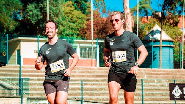 Two men jogging during a 5KM outdoor race on a sunny day, showcasing fitness and endurance.
