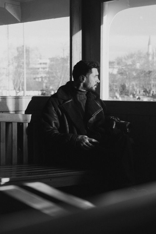 Free A man thoughtfully gazes out a window in a monochrome setting. Stock Photo