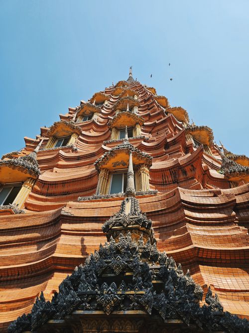 Free Dramatic view looking up at the detailed architecture of a Thai temple tower on a clear day. Stock Photo