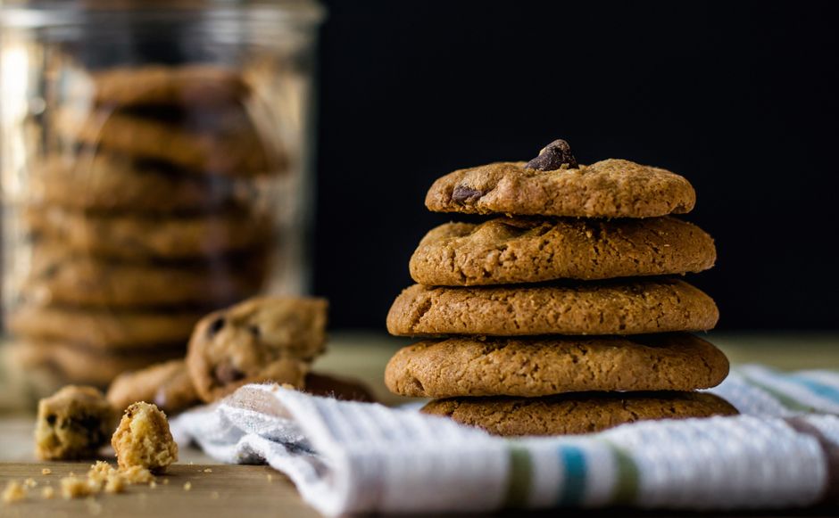 Una apetitosa pila de galletas con chispas de chocolate sobre un servilleta de tela con migas alrededor.