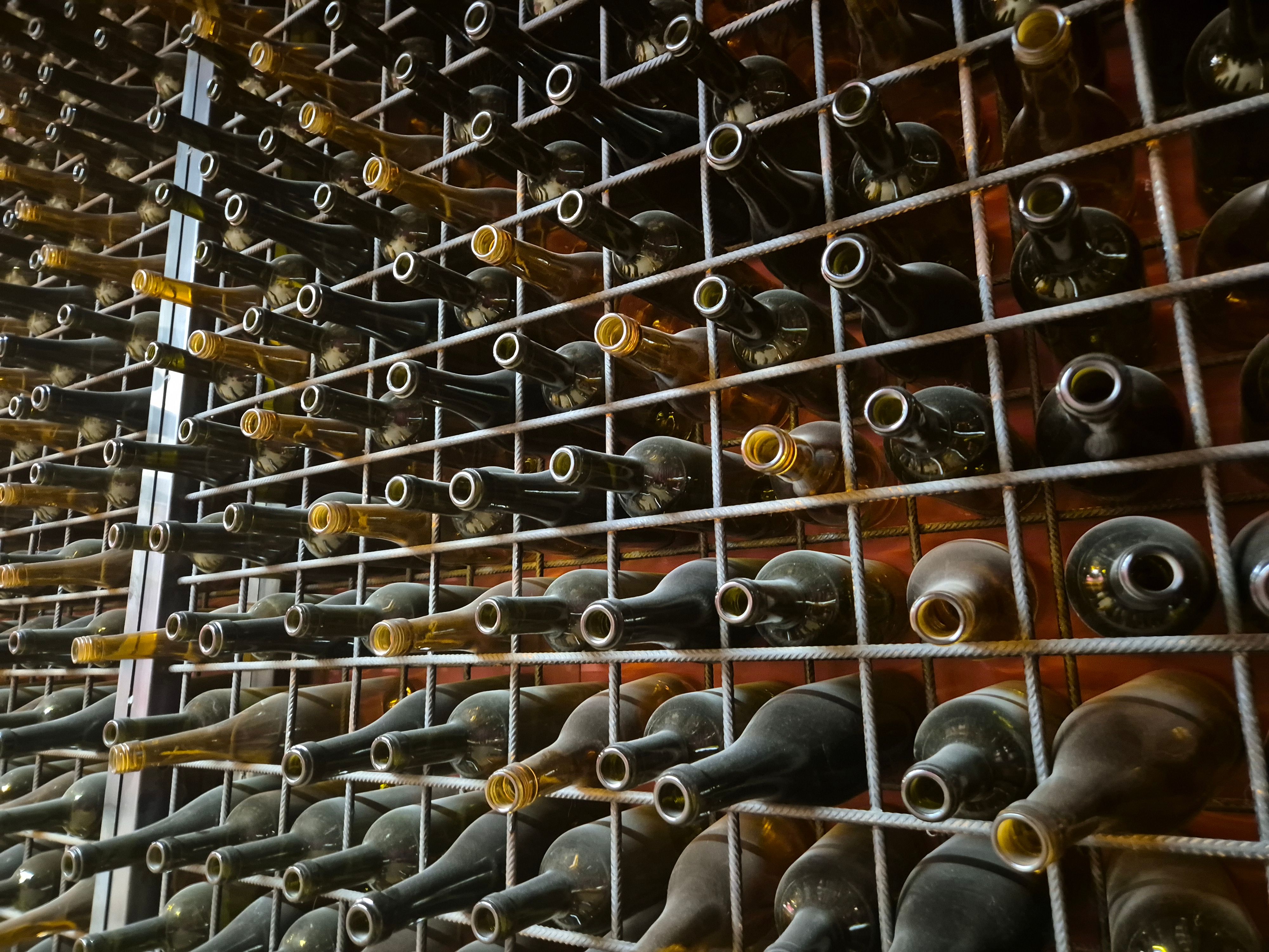Rows of empty wine bottles stored horizontally in a metal rack.