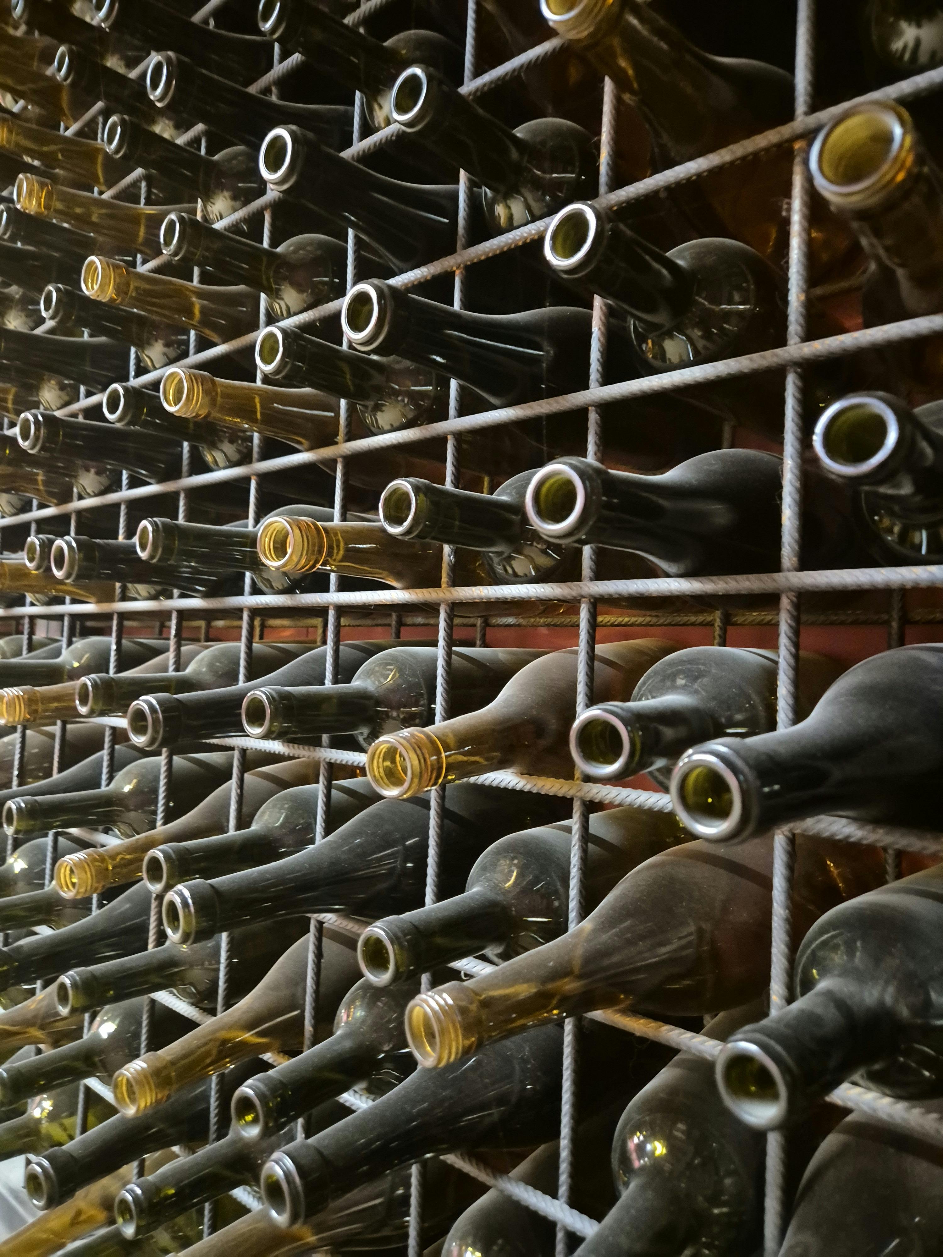 A detailed view of neatly arranged empty wine bottles in a cellar rack, showcasing symmetry and texture.