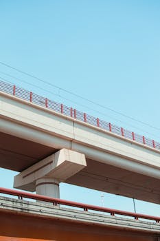 An overpass bridge with red railing captured against a vibrant blue sky.