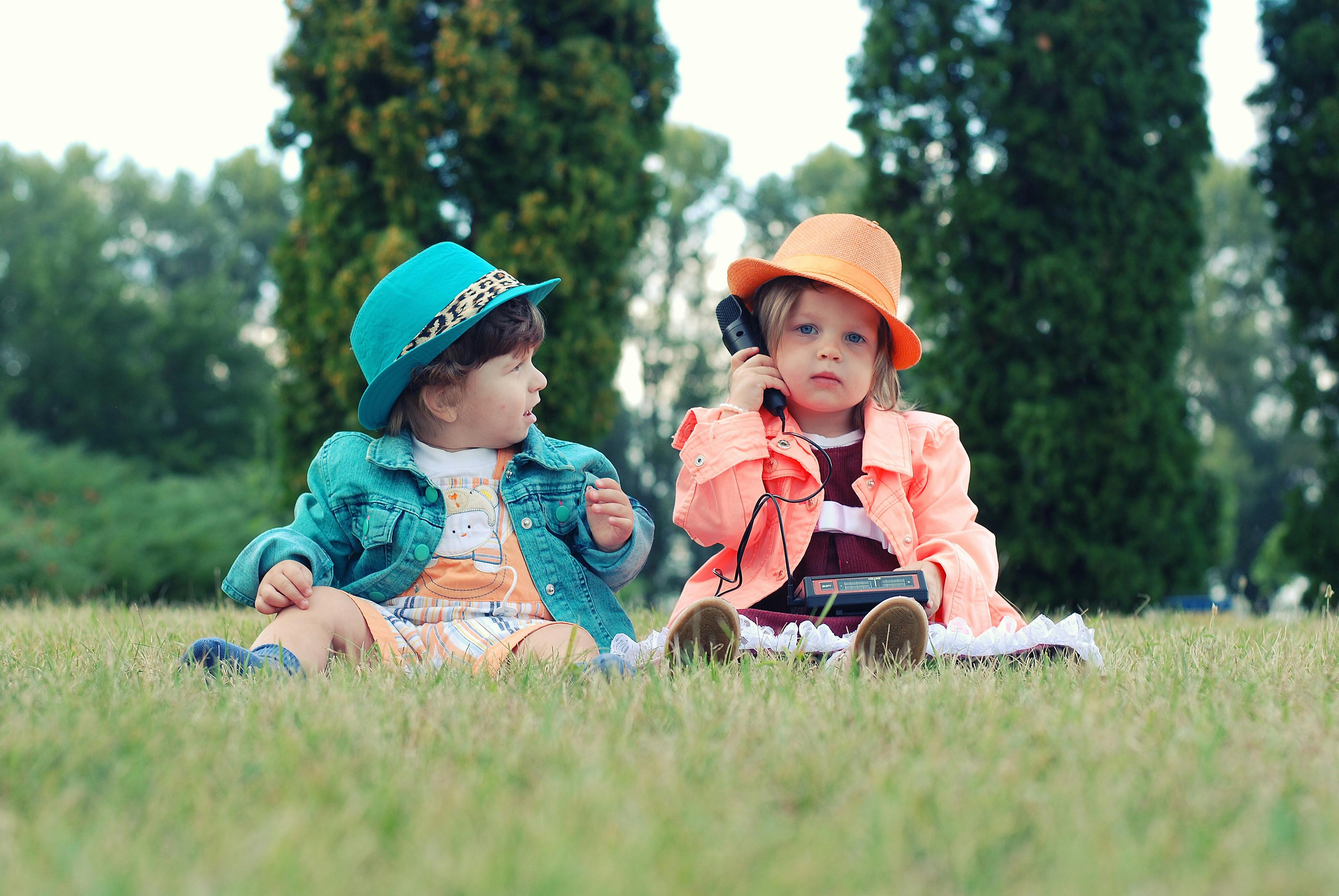 two toddlers sitting on grass field