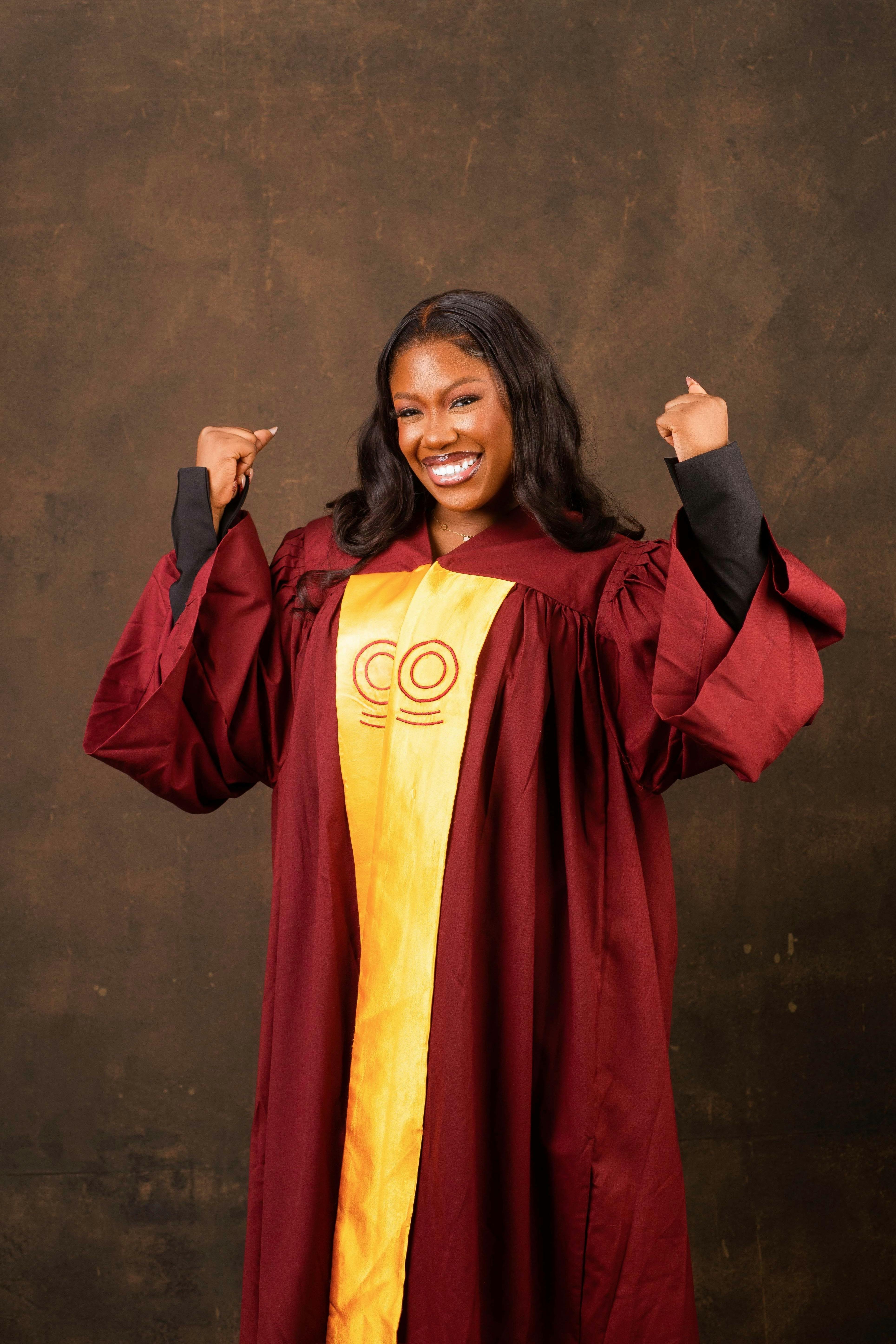De franc Una dona jove celebrant feliçment la seva graduació amb un vestit granat. Foto d'estoc