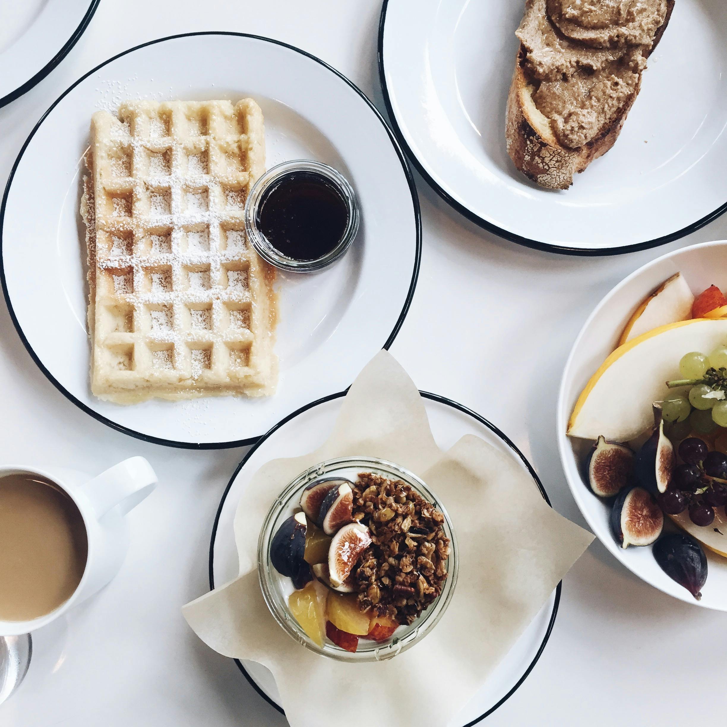 Enjoy a beautifully arranged brunch with waffles, fruit, and coffee, perfect for a relaxing weekend.