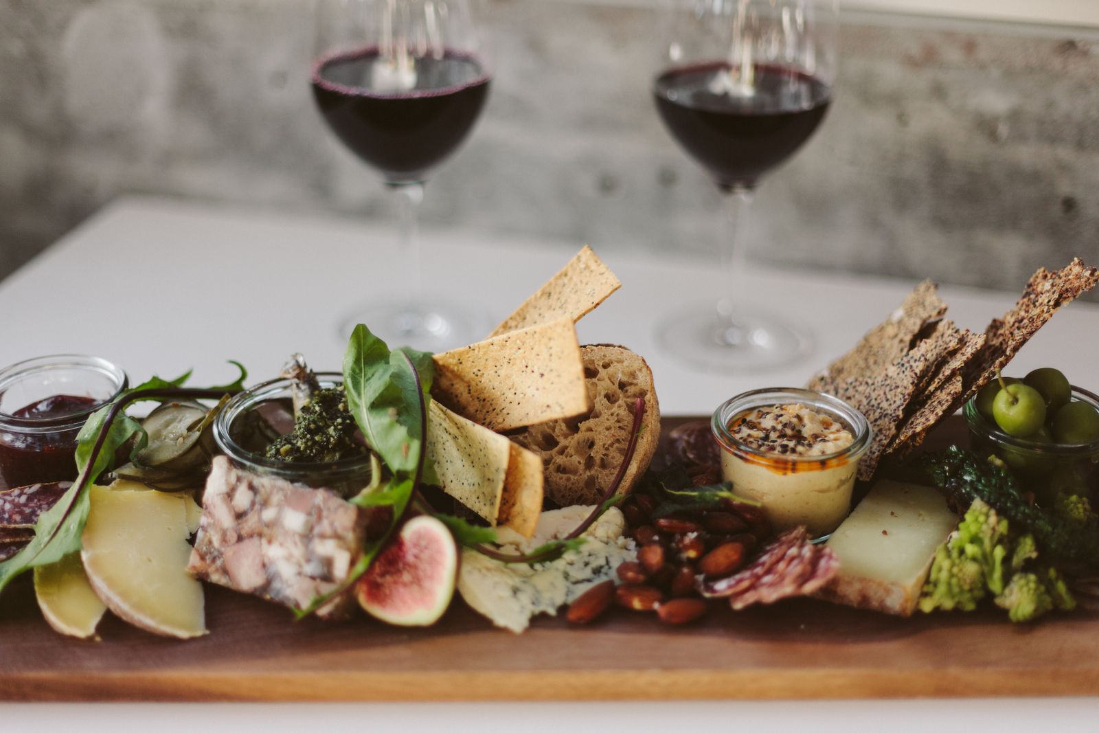 Tabla de quesos y embutidos servida junto a copas de vino