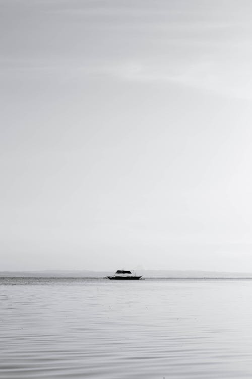 Grayscale Photo of a Boat on an Ocean