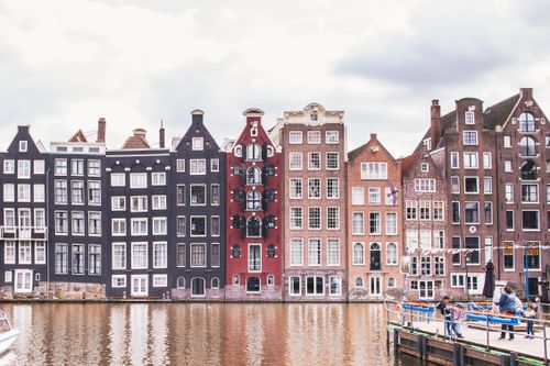 Free Historic Amsterdam canal houses reflecting in the water showcasing architectural beauty. Stock Photo