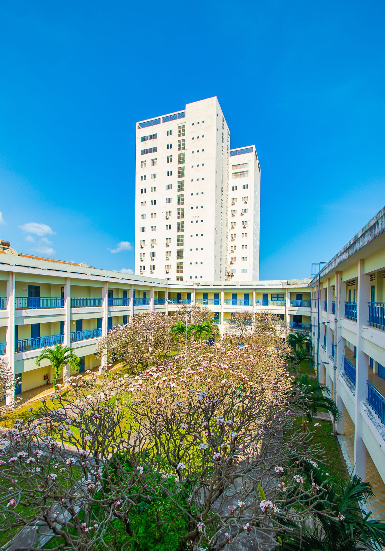 View of a modern university building with a courtyard in Quy Nhơn, Vietnam, under a clear blue sky.