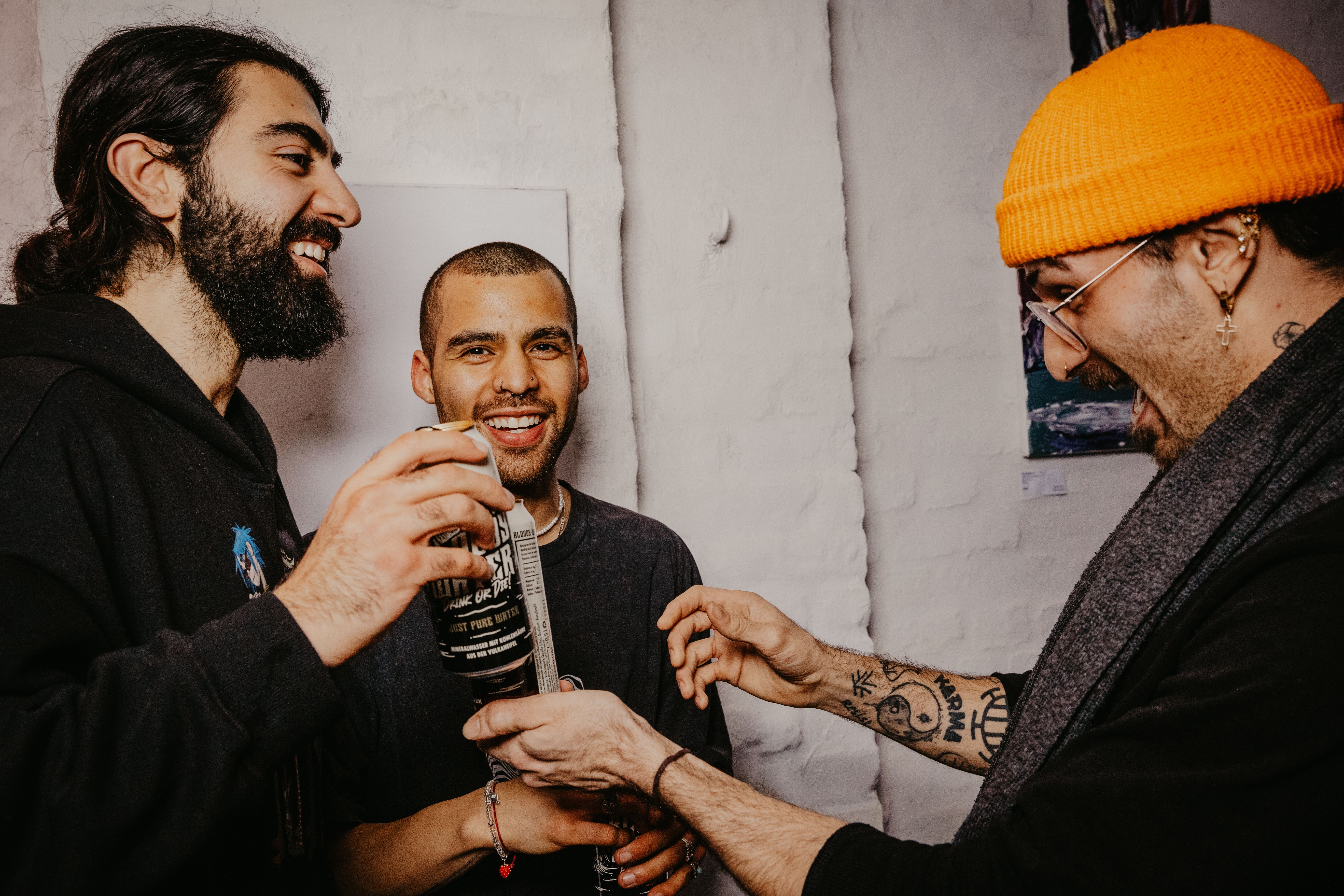 Three adult friends having fun and laughing indoors at a social event.