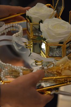 Detailed close-up of a decorative floral arrangement featuring white roses and pearls in a golden frame.