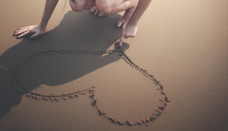 Woman Draws Heart On Sand