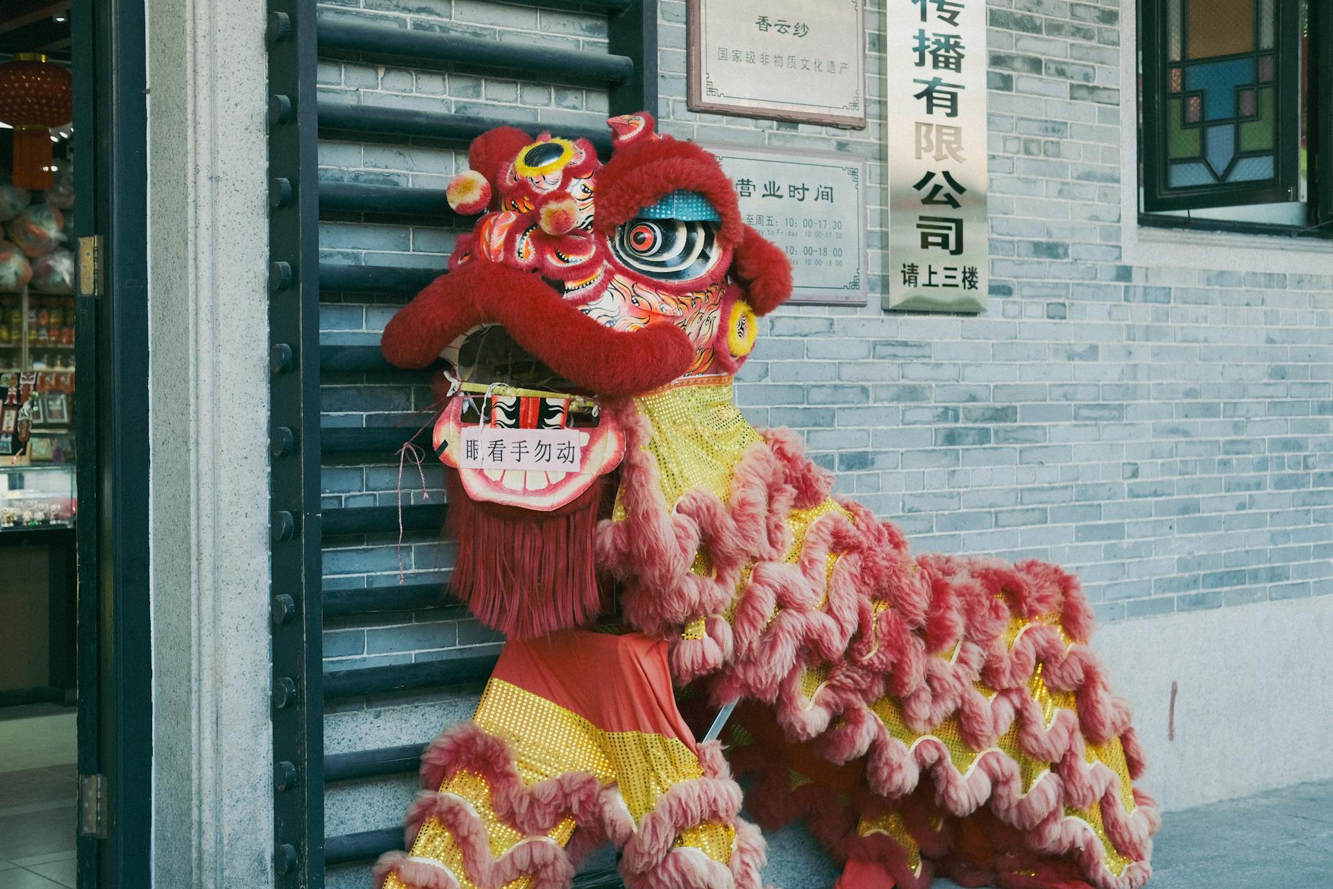 Colorful Chinese lion dance costume set against an urban storefront backdrop during a festival.