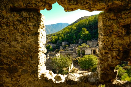 Scenic view of historic ruins in Kayaköy, Turkey framed by stone window.