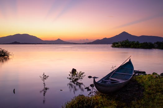 日落时分，湖面宁静，有一艘船，四周环绕着山脉和平静的水面