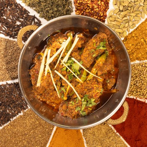 Free Delicious Indian curry surrounded by an assortment of colorful spices in a traditional bowl. Stock Photo