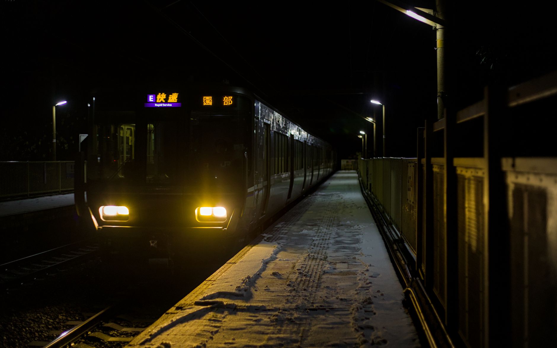 A train at Hozukyō Station in snowy Kameoka, Kyoto, Japan, during winter night.