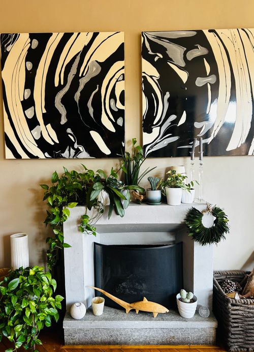 Free A stylish indoor setting featuring a modern fireplace with abstract black and white artwork and lush plants. Stock Photo