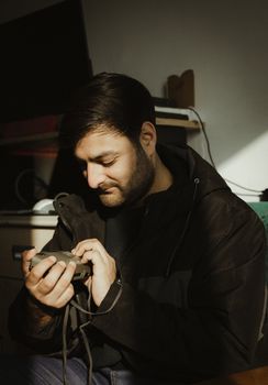 A thoughtful man inspects a vintage camera in a warmly lit indoor setting.