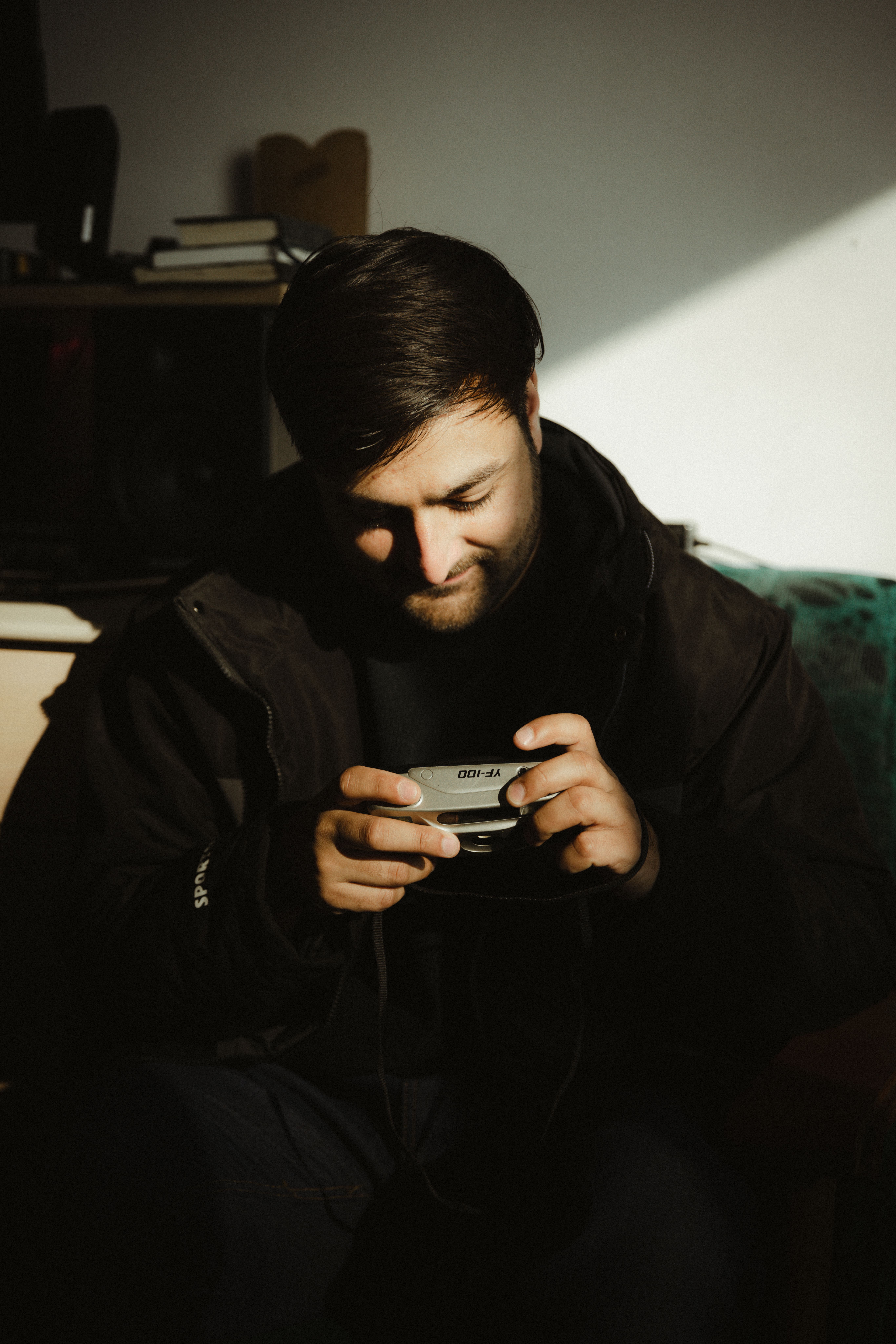 A man holding a camera, surrounded by creative shadow play in an indoor setting.