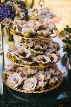 Three-tier tray with exquisite desserts, elegantly decorated with floral theme.
