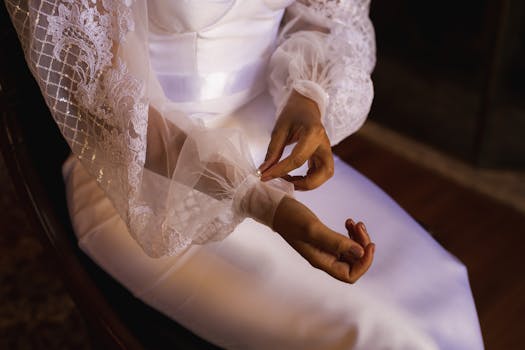 Close-up of a bride adjusting the lace sleeve of her elegant wedding dress, showcasing delicate details.