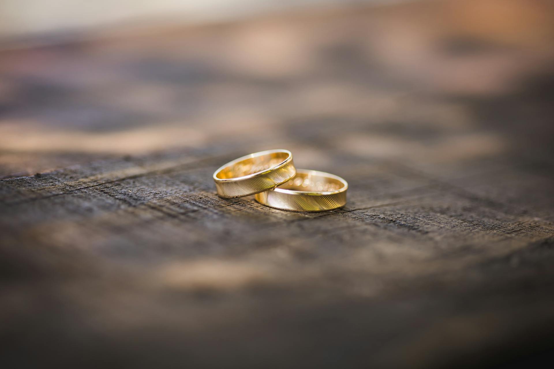 Close-up of two gold wedding rings placed on a rustic wooden surface, symbolizing eternal love and commitment.