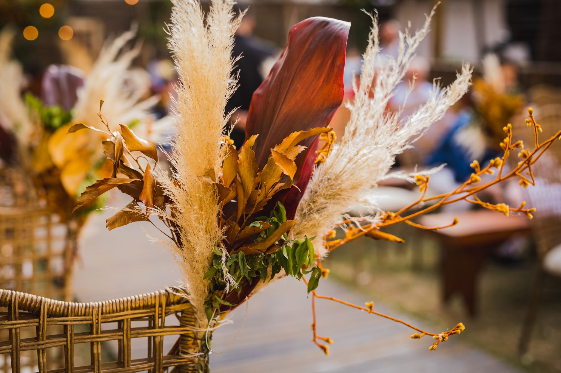 Beautiful dried floral arrangement on wicker chair at an outdoor event.