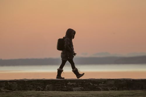 Free Silhouetted figure walking at dawn in Stamford with serene winter sunrise. Stock Photo