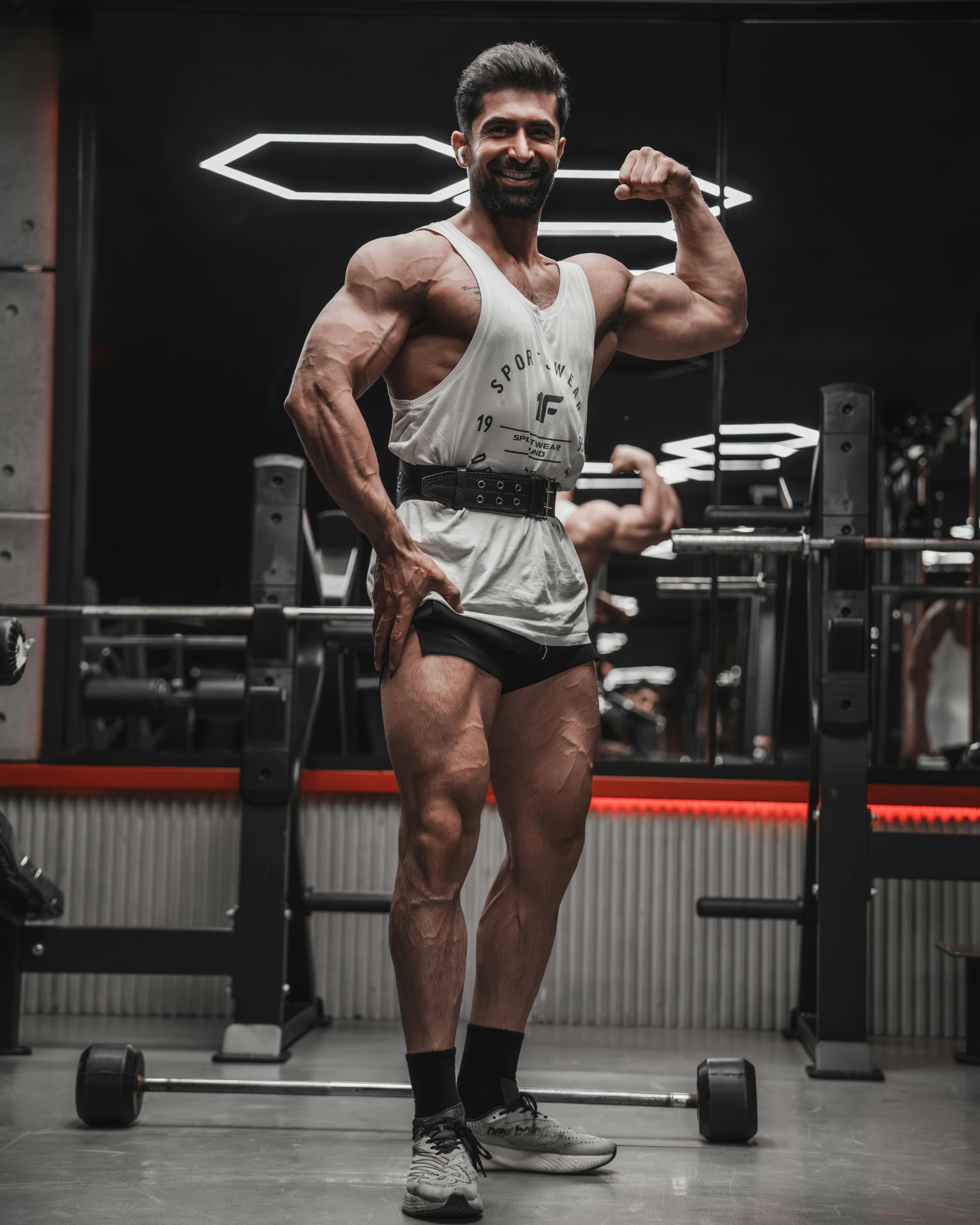 Fit woman in sportswear doing squats with dumbbells in a gym, smiling, full body workout.