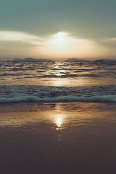 日出时分，宁静的海滩上，温柔的海浪在温暖的光芒中拍打着海岸