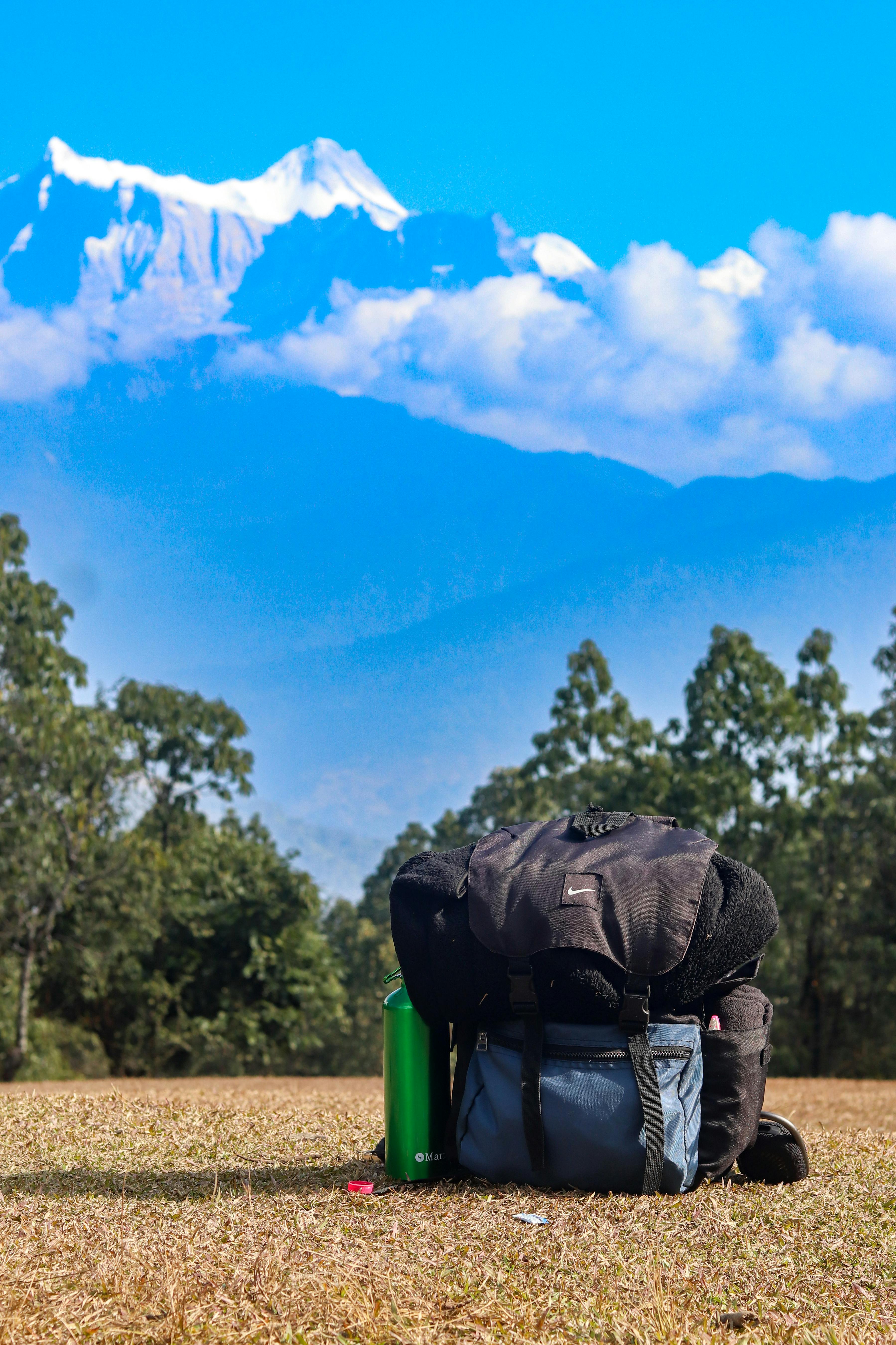 A travel backpack set against a scenic view of the Himalayan mountains in Nepal.