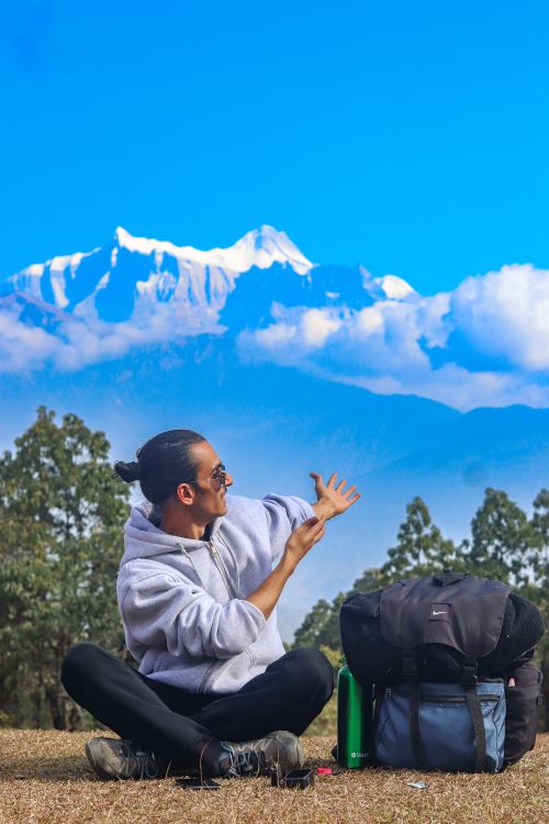 Free Man seated outdoors with stunning view of Nepal's Himalayan mountains in the background. Stock Photo