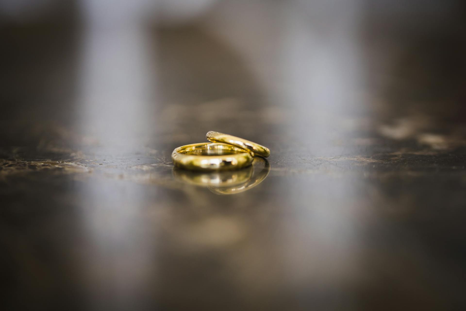 Elegant close-up of golden wedding rings on a reflective marble surface, evoking love and commitment.