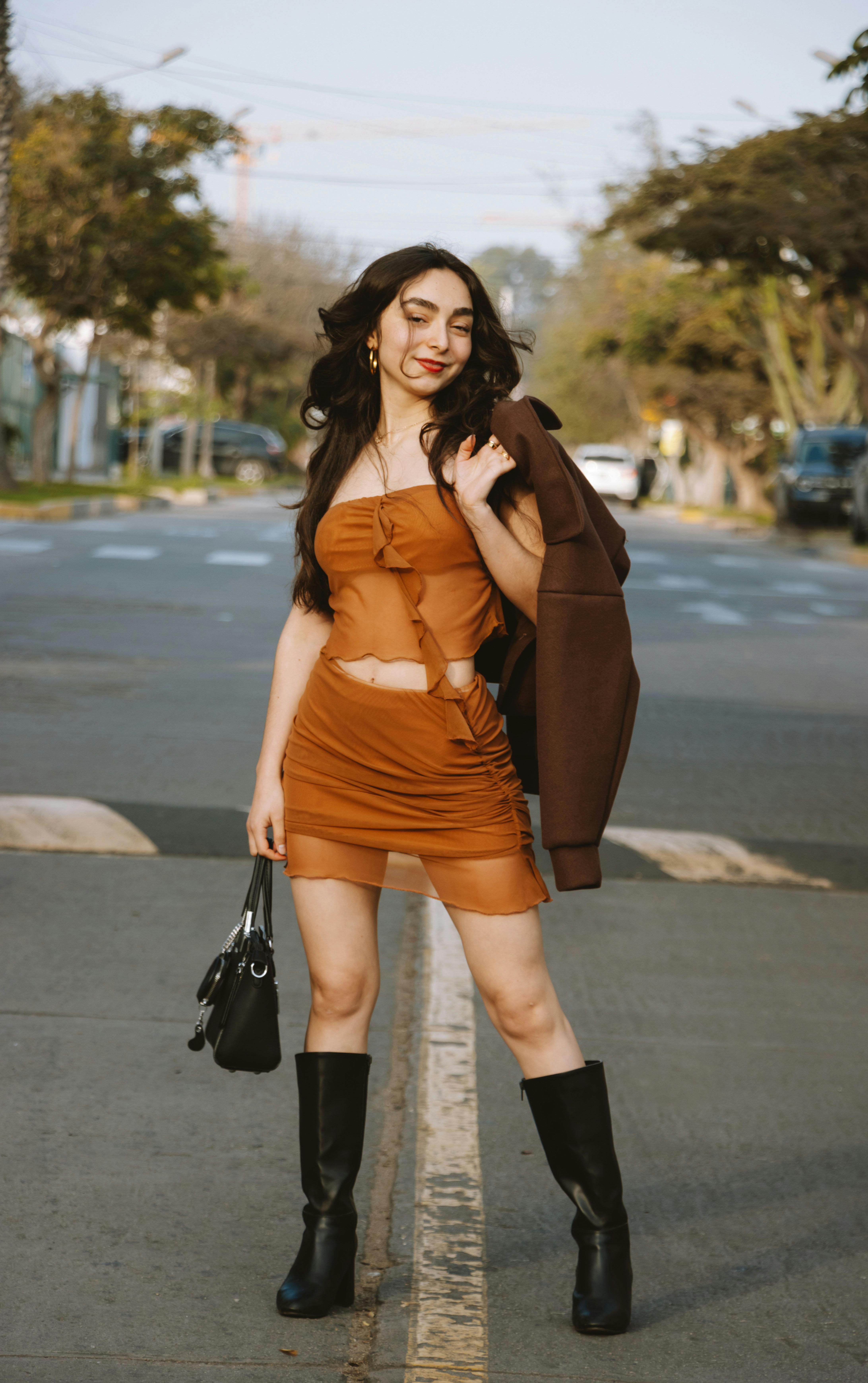 bezplatná Stylová žena v hnědém oblečení sebevědomě kráčející ve slunné ulici Lima. Základová fotografie