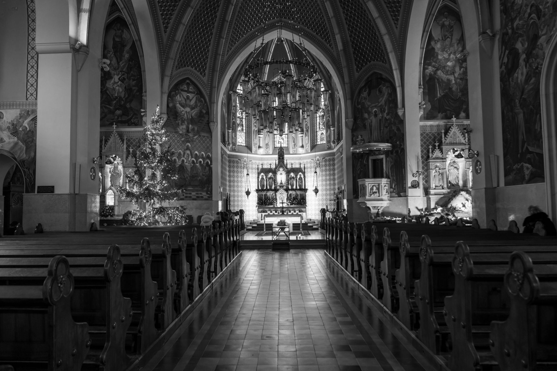 Black and white photo of the interior of a church in Bled, Slovenia, featuring Gothic architecture and a chandelier.