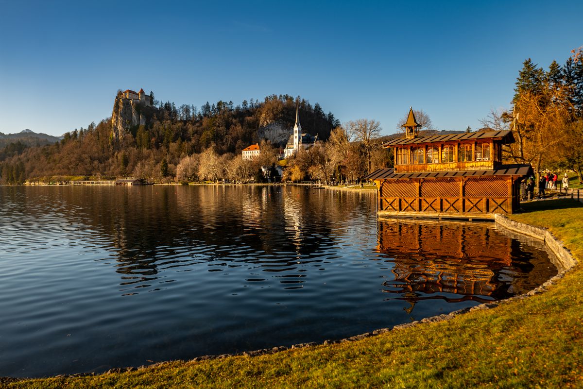 Lake Bled in autumn, with coloured forest around the shore