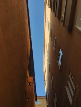 View between two tall urban buildings with a clear blue sky above.