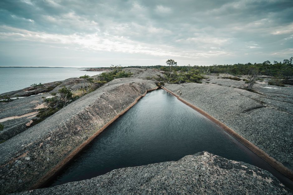 A tranquil rocky coastline with a natural water pool in the Åland Islands.