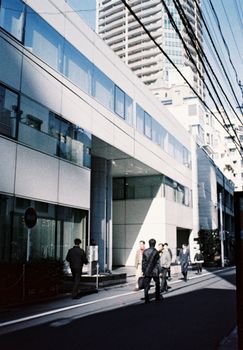 Street scene with pedestrians and modern buildings in Tokyo, Japan.