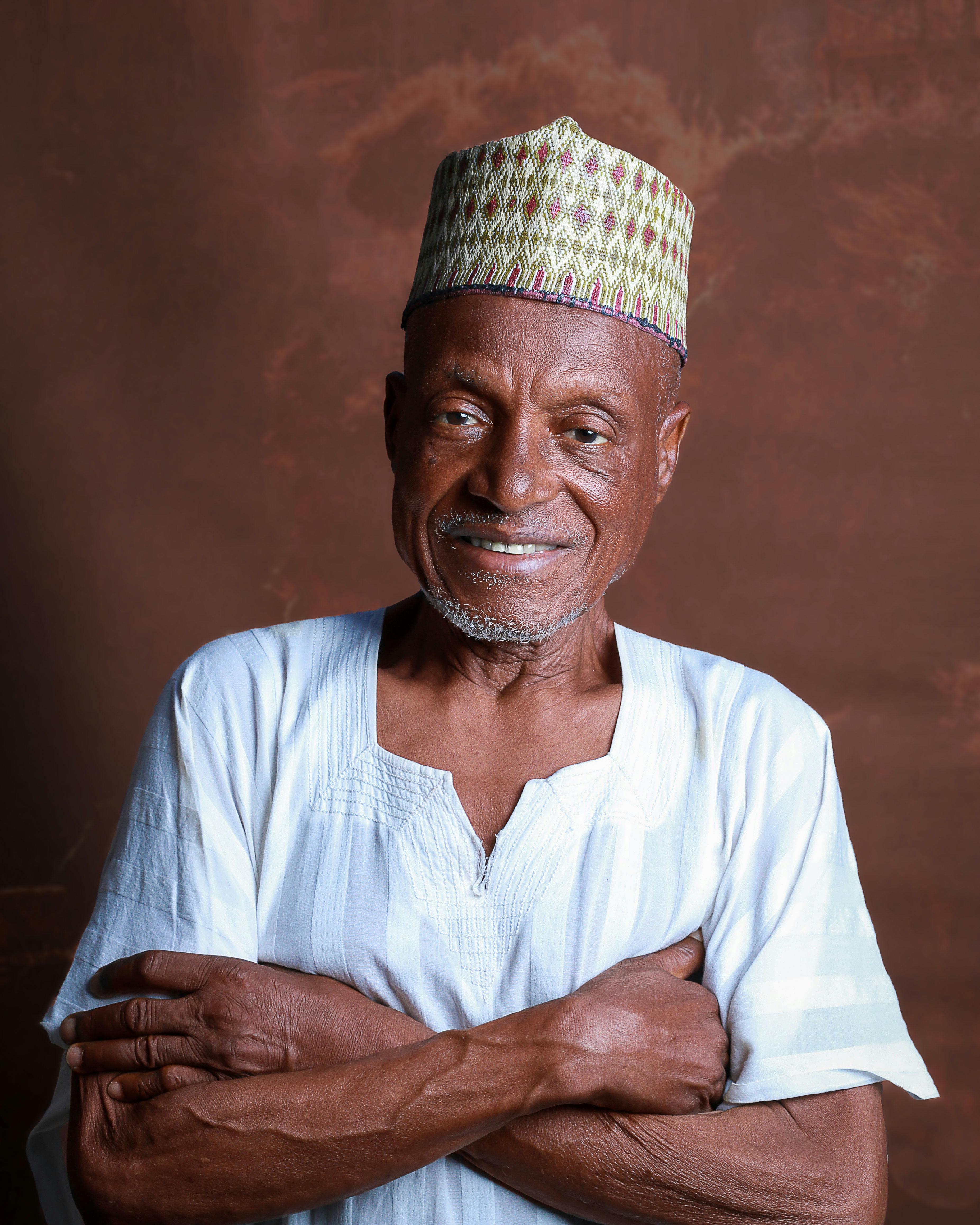 Elderly man wearing traditional African clothing, smiling confidently.
