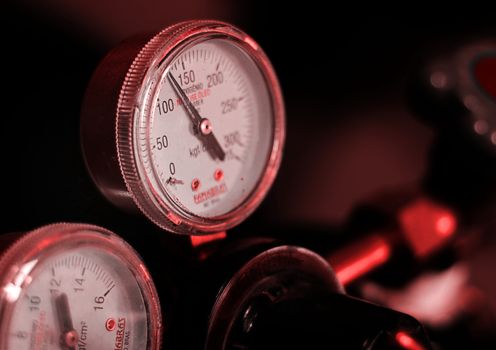 Detailed view of pressure gauges with red lighting in an industrial setting.