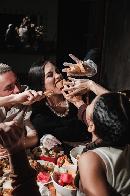 Free A lively group enjoys a festive meal with a playful food fight at the table. Stock Photo